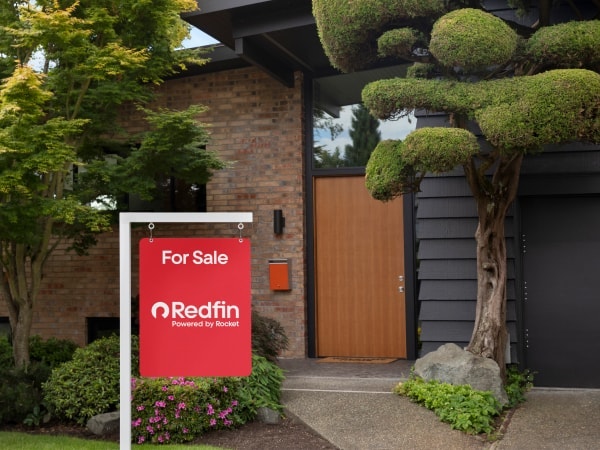 The exterior of a modern house with a large Redfin yard sign