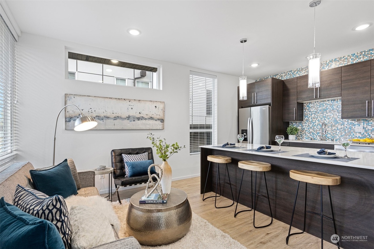 a galley kitchen with bar seating, with a sofa and end table clearly in frame. they are one somewhat cramped room.