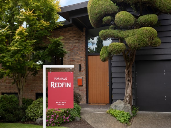 The exterior of a modern house with a large Redfin yard sign